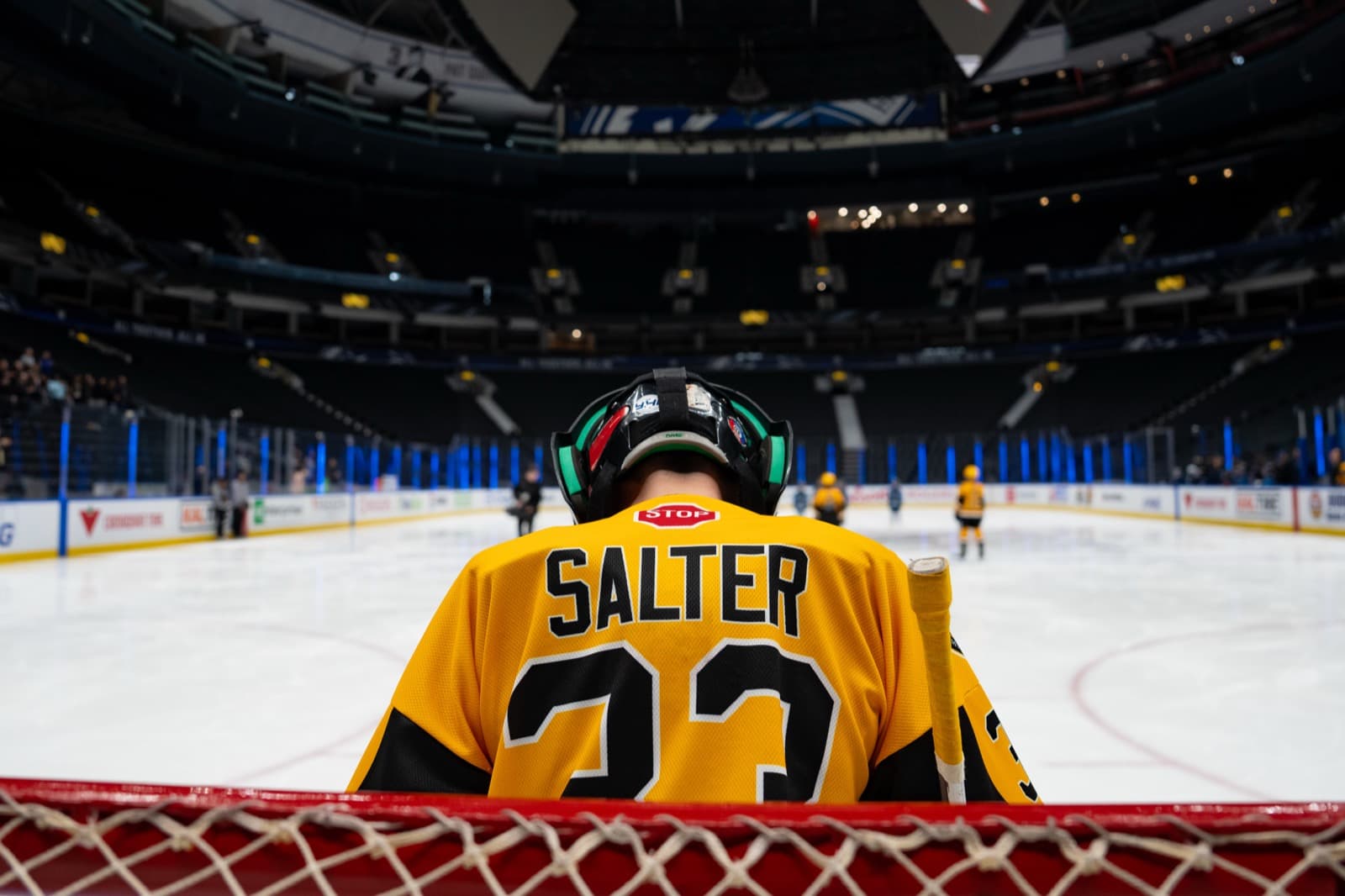 A Comets player viewed from behind the net, looking out at the vast Rogers Arena ice surface and seating bowl