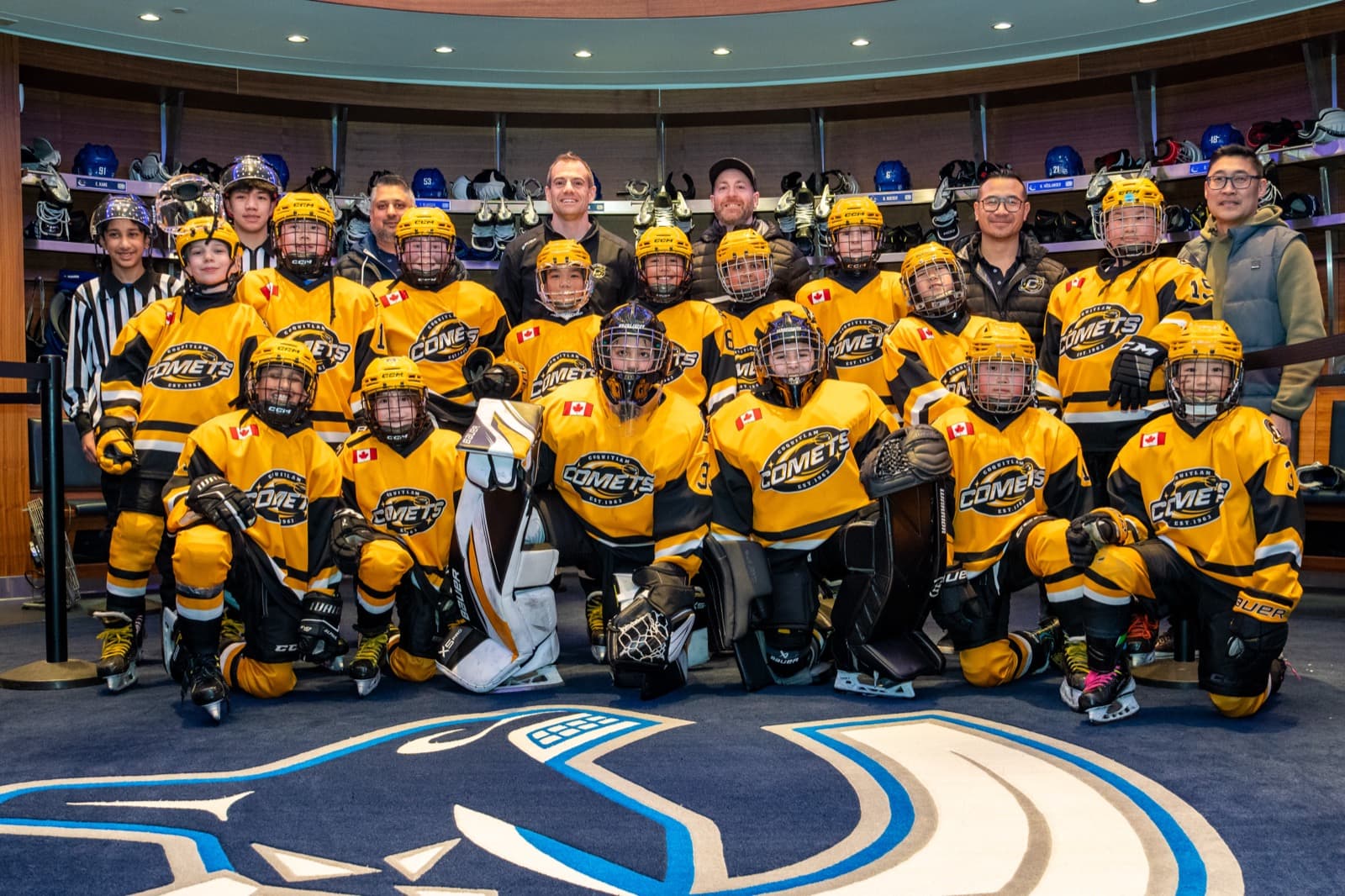 The Coquitlam Comets team and coaching staff pose for a group photo in the Canucks home dressing room